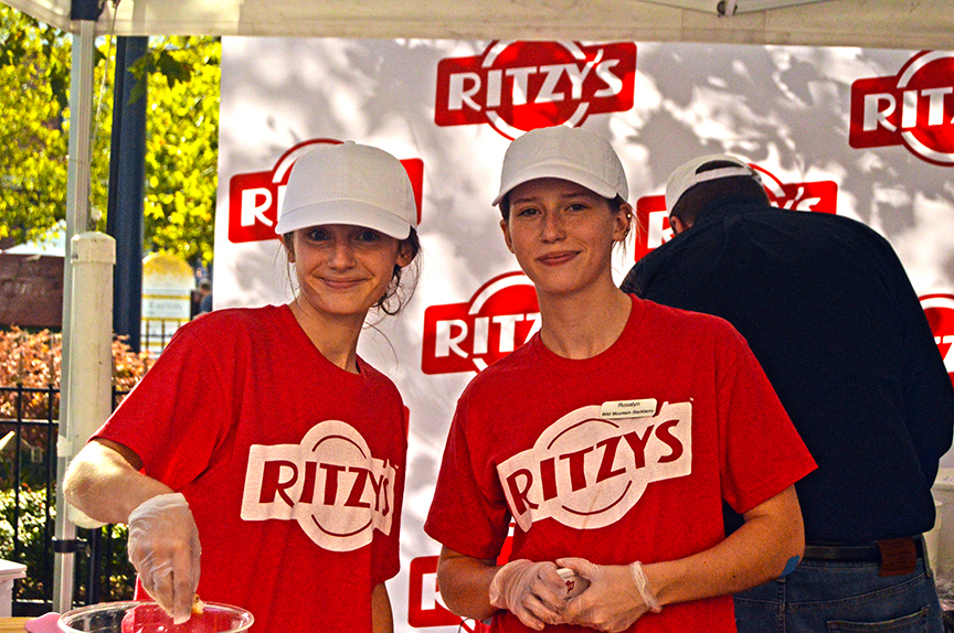 Two women in red shirts and white caps from Ritzy's at the Mac and Cheese Festival