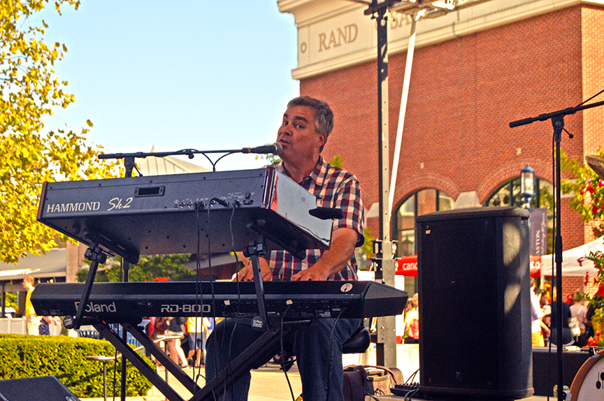 Seated keyboardist sings into mic at event